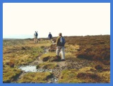 Anne following other walkers along the muddy path over White Edge Moor .