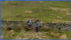 Crossing the stile at the bottom of the steepest part of the descent .